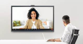 A man holds a videoconference with a smiling woman on a new MAXHUB flat panel display.