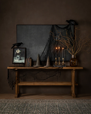 An wood entryway credenza with witches hats, twig foliage, and a fake crow