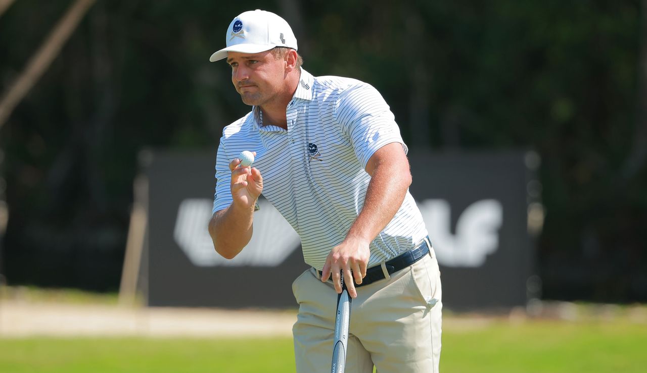 DeChambeau waves to the crowd after holing a putt