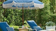 Amazon fringe sun umbrella hanging overhead two sun loungers in a verdant green backyard