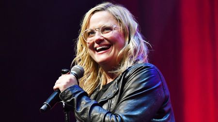 Amy Poehler holds a microphone