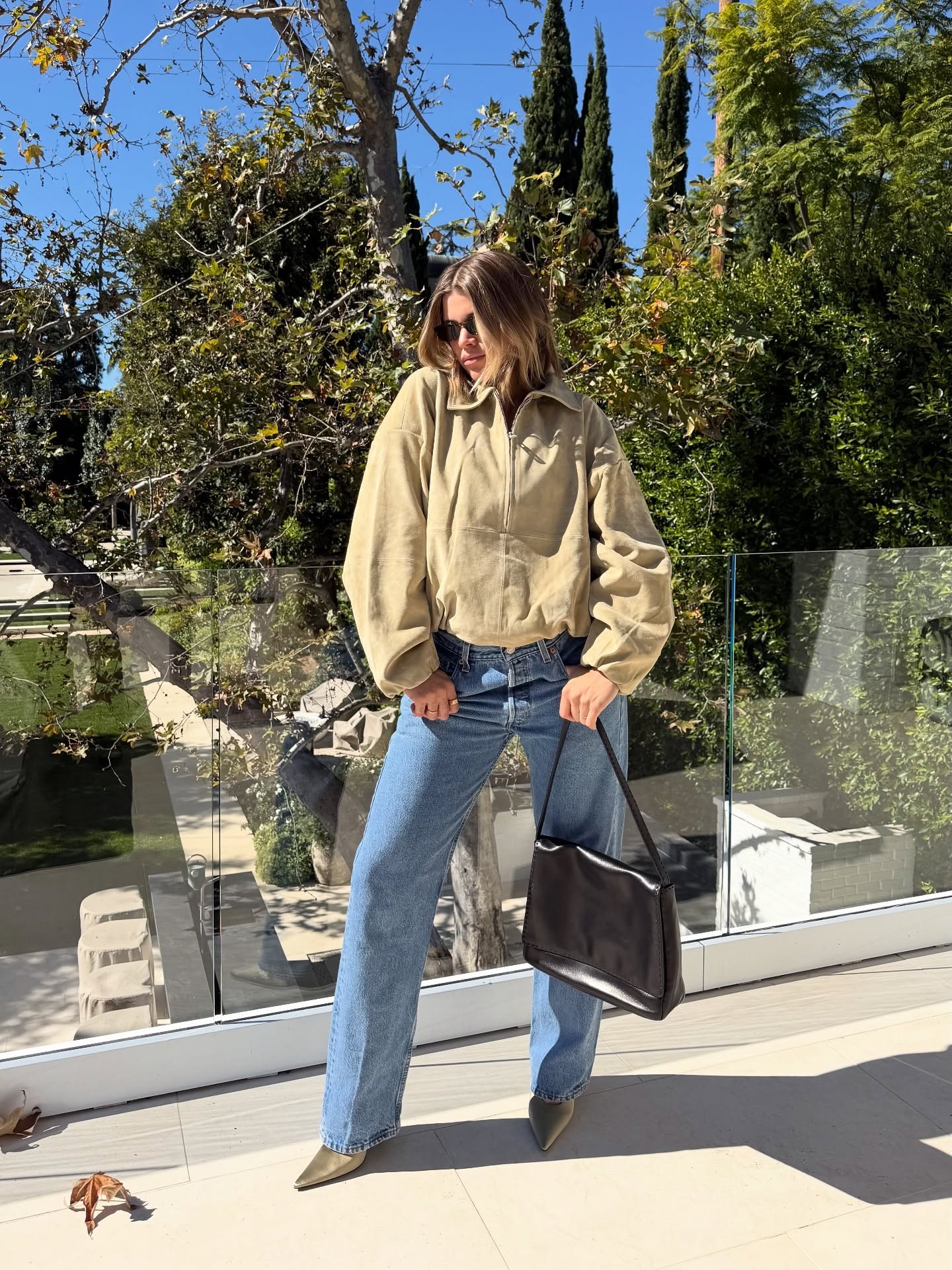Sofia Richie Grainge wearing a suede anorak, light-wash jeans, and a black bag.