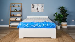 Image shows the white and blue thick protective plastic covering on the Saatva Classic mattress just after it is delivered to our sleep studio for testing