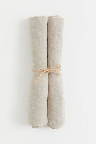 two beige linen napkins rolled up and tied together with some twine