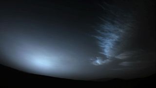 still image of the sun peeking through clouds on mars with a lower, drifting cloud at right