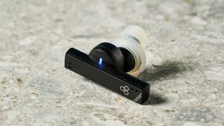 a photograph of one black earbud by final with a long, angular stem and black casing