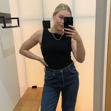woman wears black top and blue jeans 