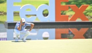 Fowler lines up a putt with the fedex logo behind him