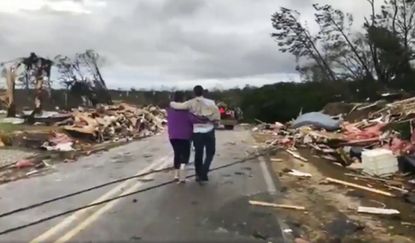 People look at tornado damage in Lee County, Alabama.