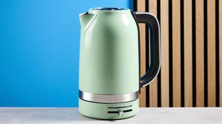 the kitchenaid 1.7L kettle in pistachio photographed on a white marble counter with a blue background