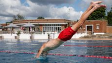 A boy with red trunks diving into Parliament Hill Lido