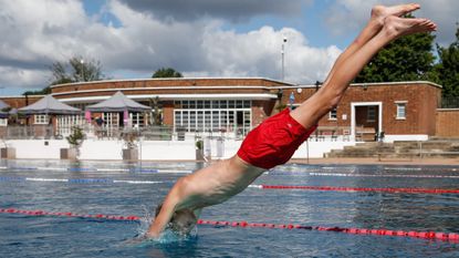 A boy with red trunks diving into Parliament Hill Lido