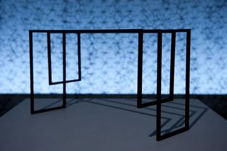 Black steel rectangle shaped table, photographed with black mesh hanging from the wall