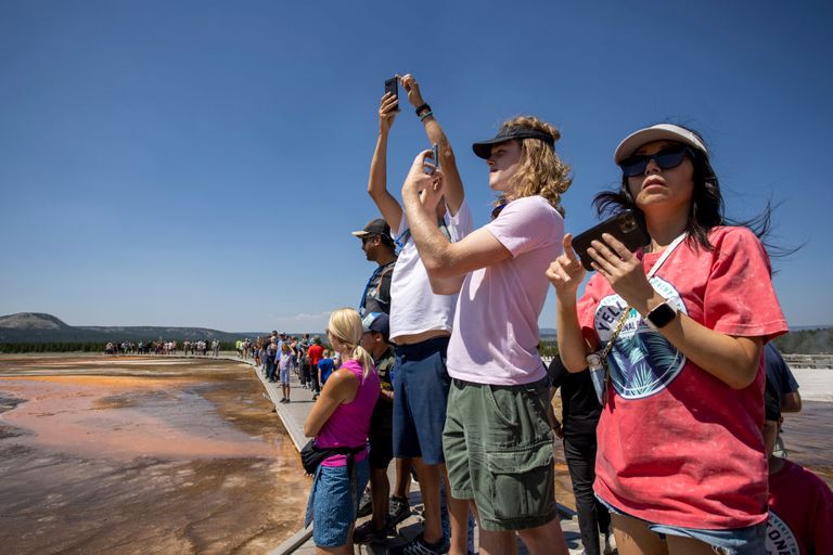 tourists take photos at yellowstone national park