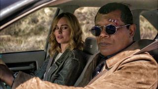 Nick Fury looks in a rear view mirror as Carol Danvers watches on in Captain Marvel