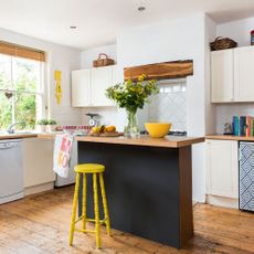 kitchen area with white wall and wooden floor and yellow stool and wooden counter