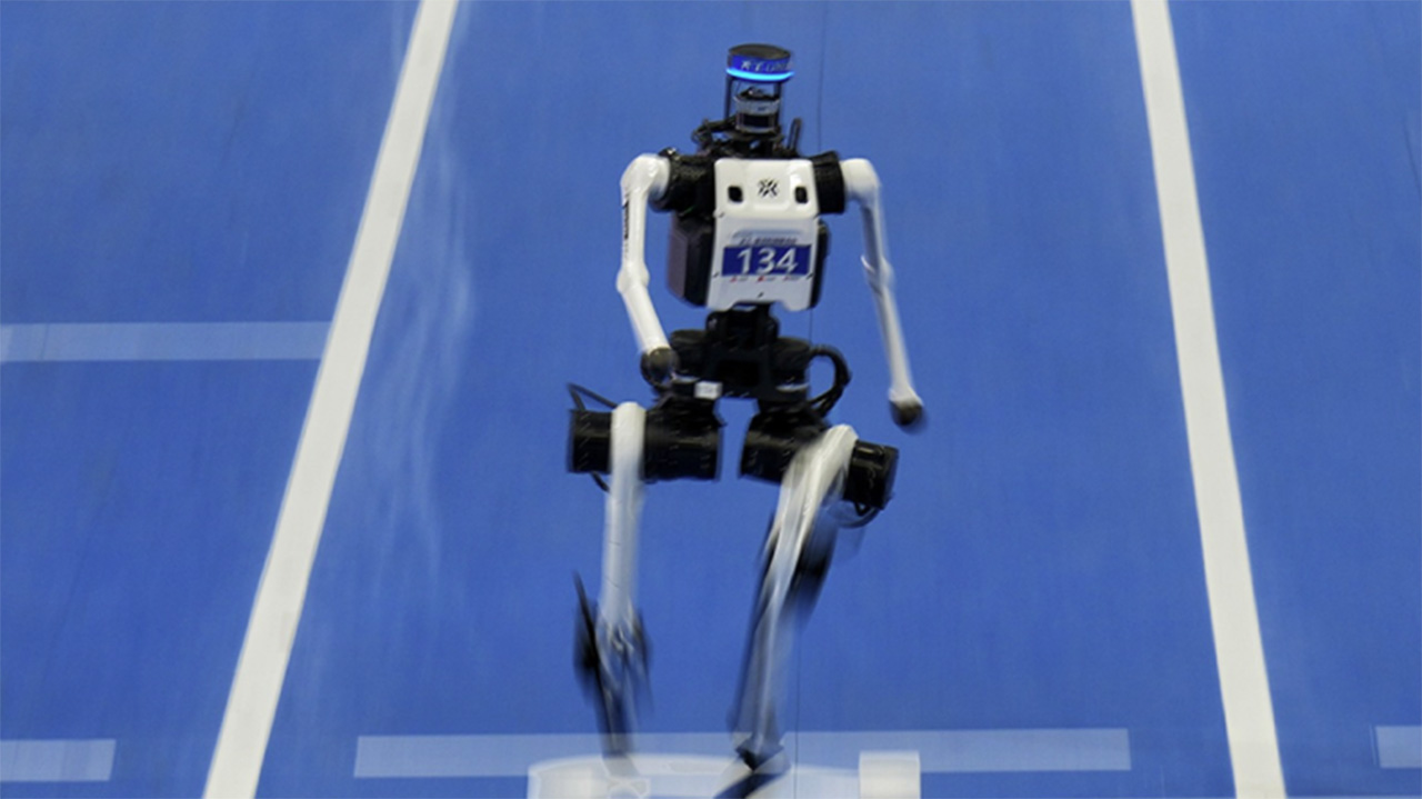 A humanoid robot runs on a blue track