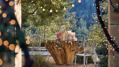 a patio with wooden table and metal chairs and string lights hung around