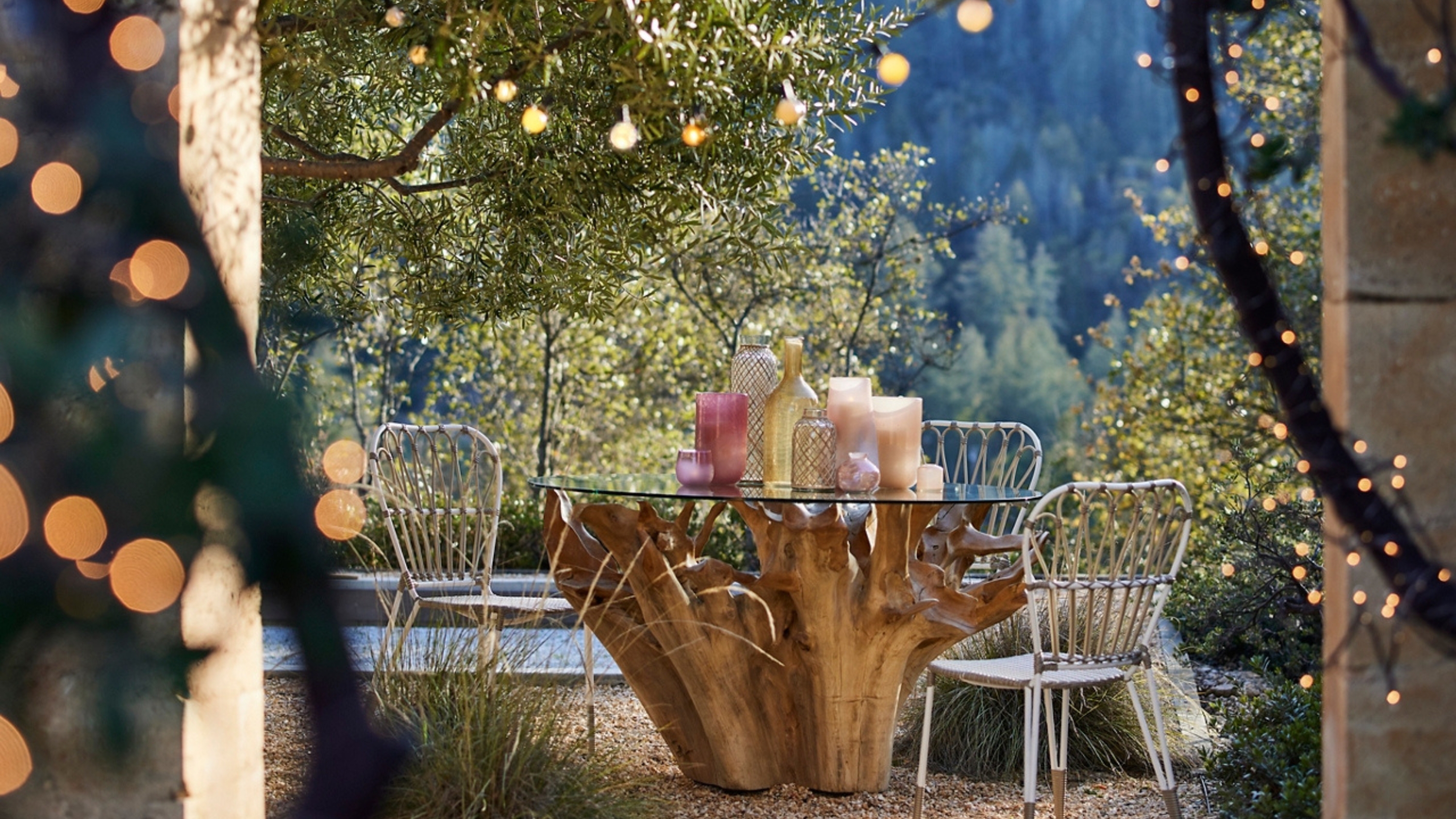 a patio with wooden table and metal chairs and string lights hung around