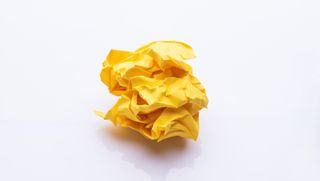a crumbled piece of yellow paper on a white background meant to symbolize stress