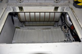 Aboard the space shuttle Endeavour, under the seats where astronauts sat for launch and landing, is a locker that held the lithium hydroxide (LiOH) canisters used to clean the orbiter's air of carbon dioxide. Lifting out that container offered a pathway to the water tanks.