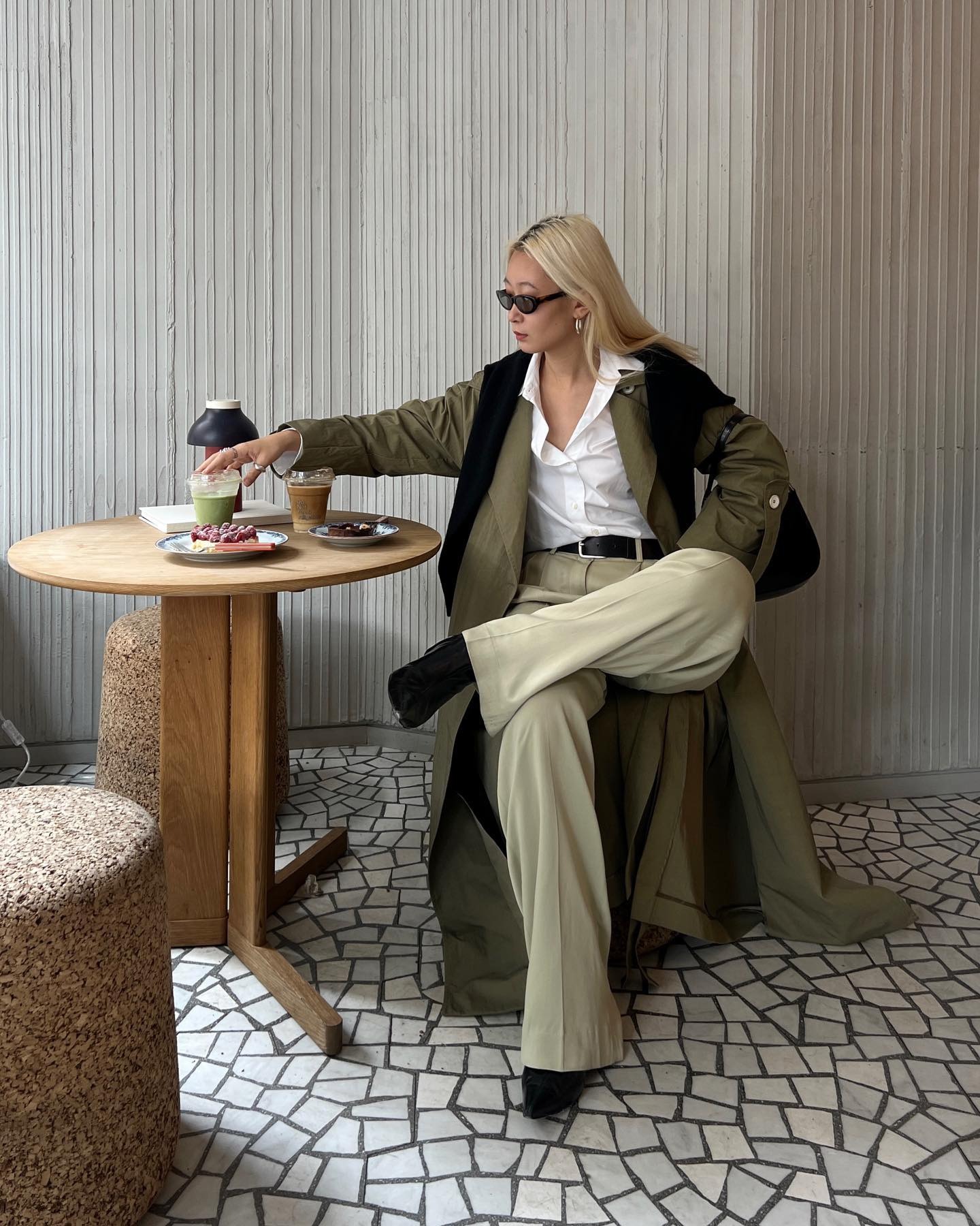 A woman sitting at a cafe in an autumnal outfit with creamy blonde hair