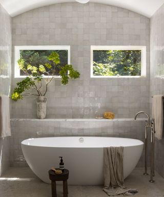 bathroom with zellige tiles contemporary bath and arched wall with high windows and views of trees