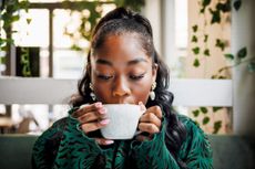 A young woman indulges in the aroma of her coffee, closing her eyes to savor the moment