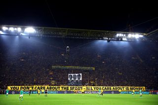 Borussia Dortmund fans hold a banner up reading 'You don't care about the sport - All you care about is money!' during the UEFA Champions League match between Borussia Dortmund and Newcastle United at Signal Iduna Park on November 07, 2023 in Dortmund, Germany.