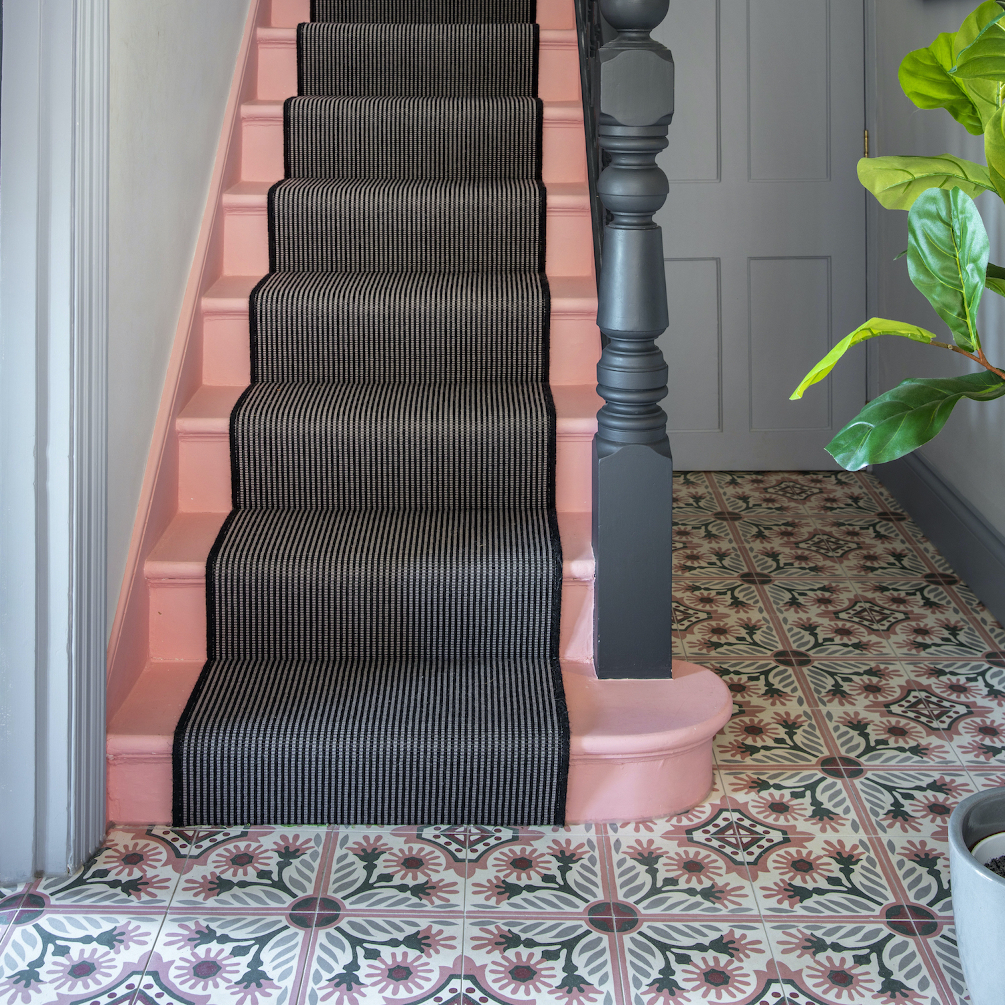 Hallway with patterned tiles and pink steps, black runner