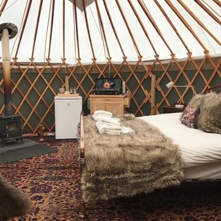 Inside of luxury tent with bed, stove, fridge on patterned carpet