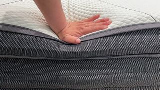 A hand pressing down on the edge of the Sleeping Duck Mach II mattress