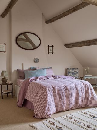 A big bed dressed in pink and white gingham bedding in a farmhouse style light pink bedroom