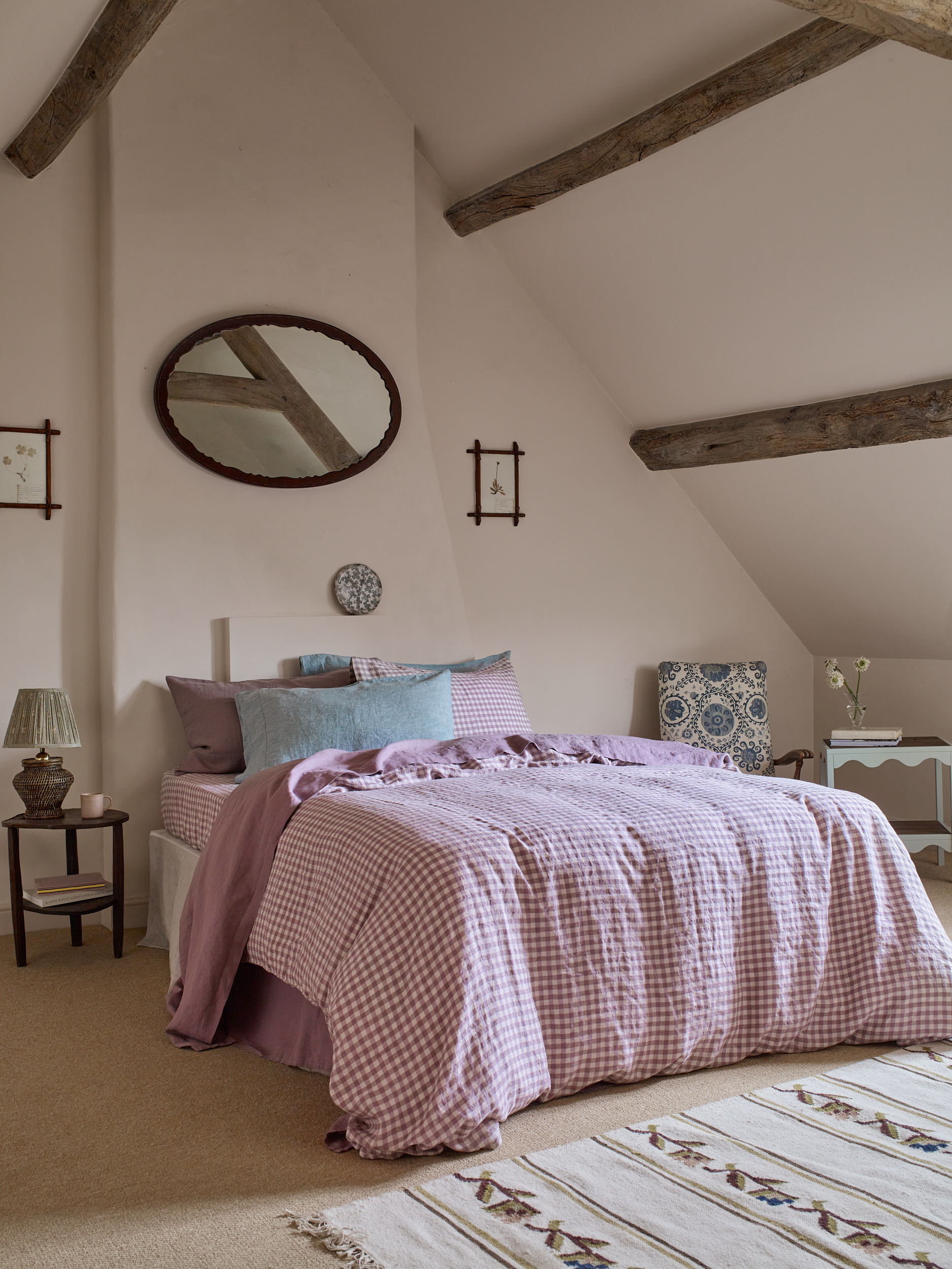 A big bed dressed in pink and white gingham bedding in a farmhouse style light pink bedroom