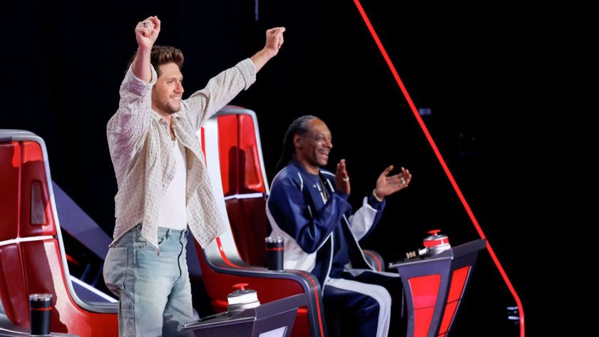 Niall Horan raises his arms above his head in celebration as Snoop Dogg smiles and claps while watching a performance on The Voice Season 28.