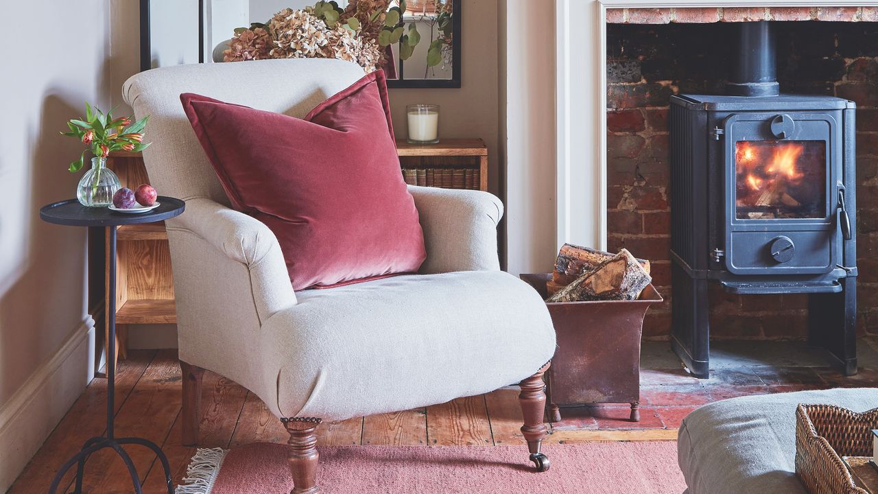 cream chair in cottage living room with woodburning stove and small antique side table