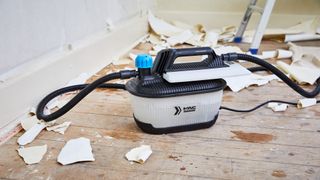 wallpaper steamer on wooden floorboards with wallpaper debris around it