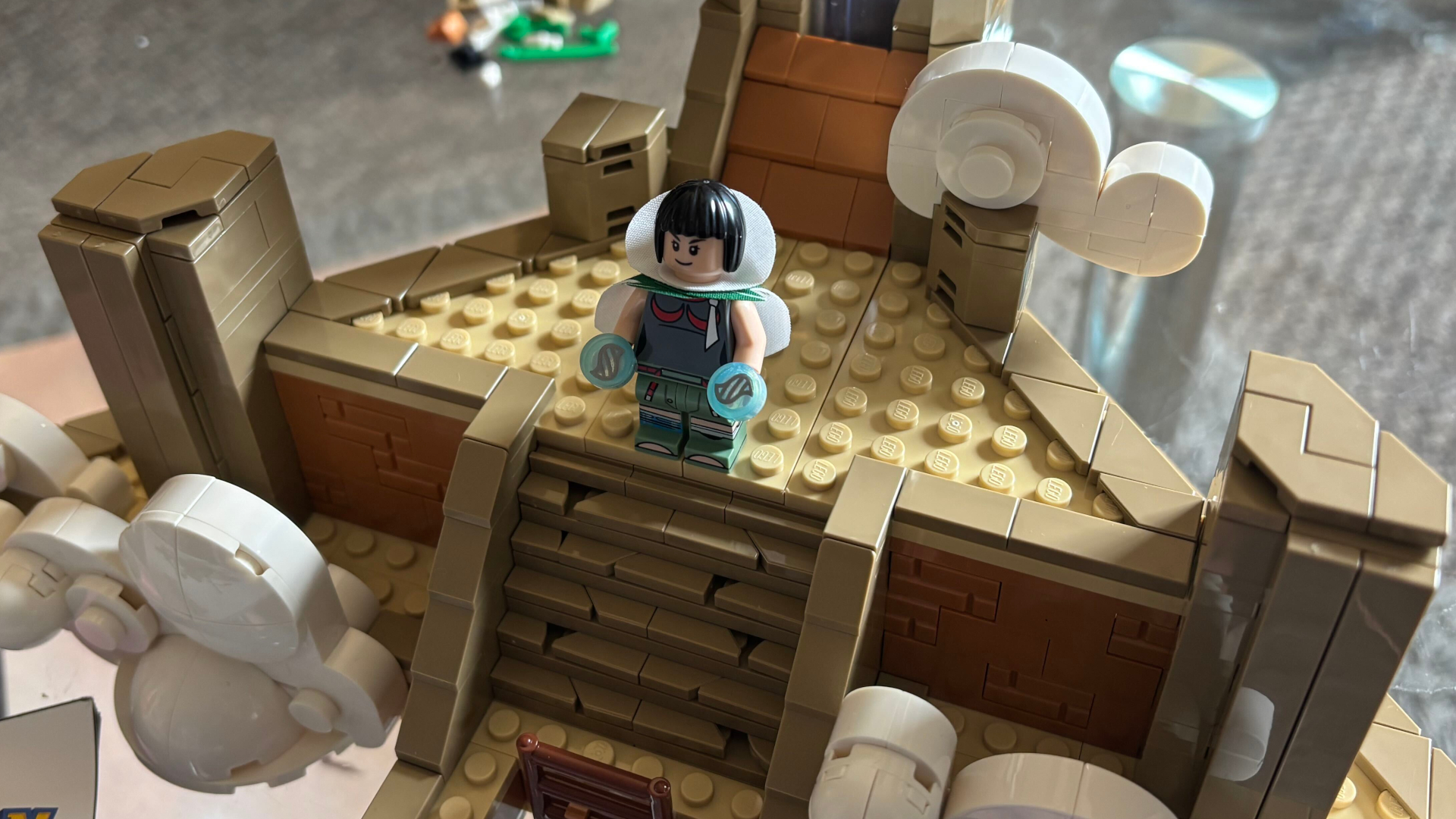 A Lego minifigure on a plinth stand amongst clouds