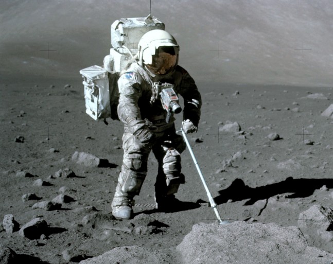 Apollo 17 astronaut Harrison Schmitt retrieves lunar samples during his December 1972 mission, his spacesuit dirtied by clinging lunar dust.