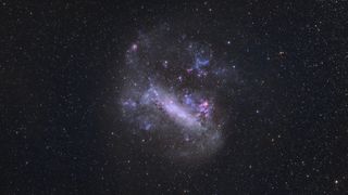 The Large Magellanic Cloud appears as a hazy purple cloud against a background of stars. 