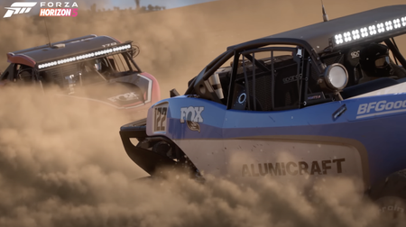 Two cars race bumper to bumper, dust billowing from their wheels