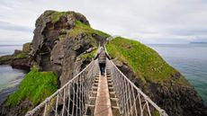 A man crossing the Carrick-a-Rede Rope Bridge in Northern Ireland