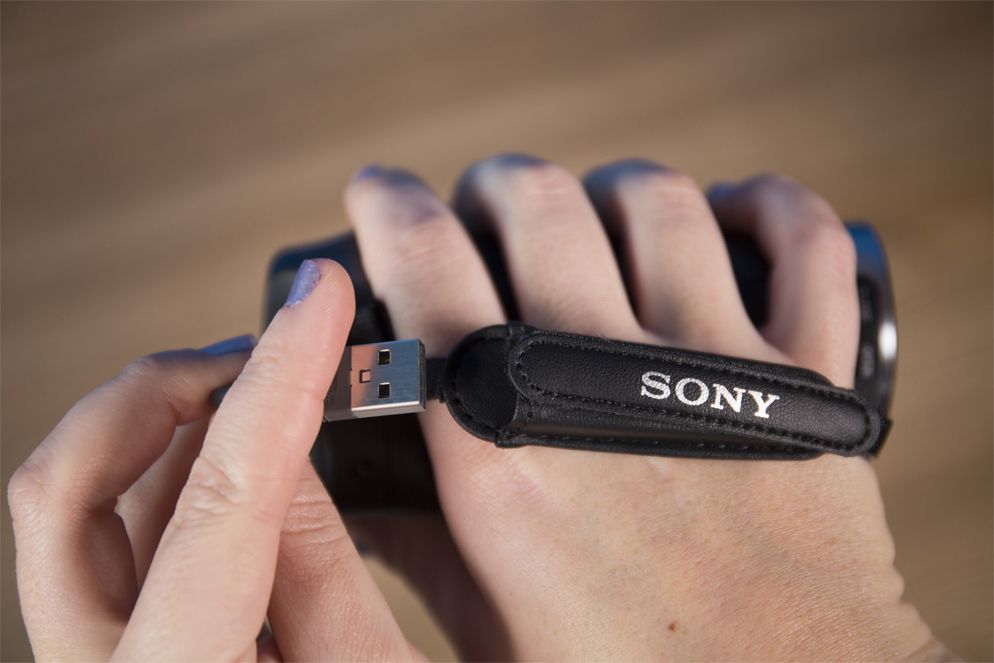 You charge the Sony Handycam HDR-CX405 with a USB cord that is permanently attached to the camcorder and secures within the hand strap.