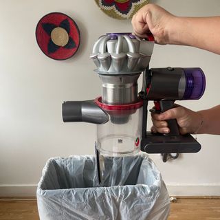 Emptying the Dyson V8 Absolute in a white room into a bin bag in a bin