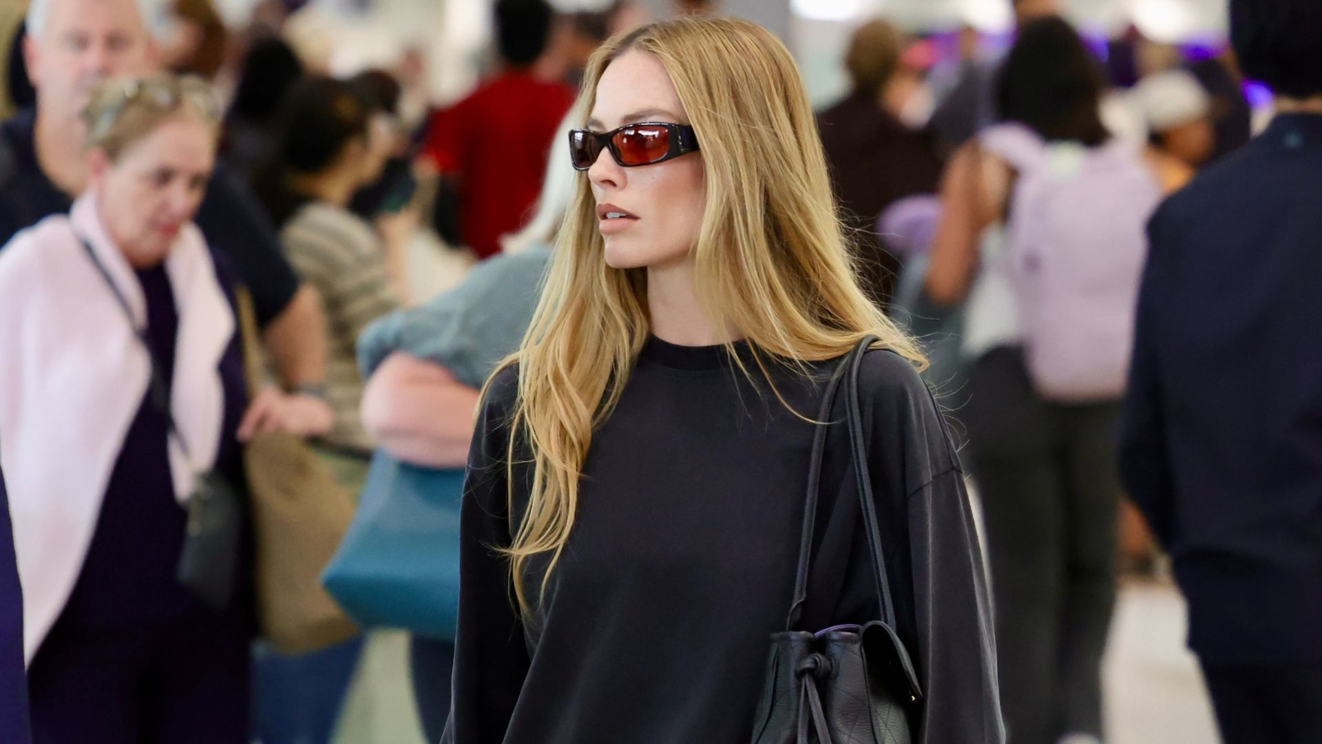 Margot Robbie walks through the airport wearing mesh ballet flats and long shorts. 