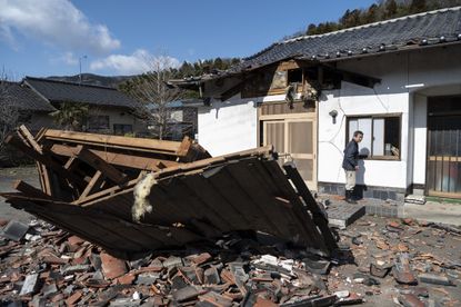 A man surveys wreckage after an earthquake in Japan