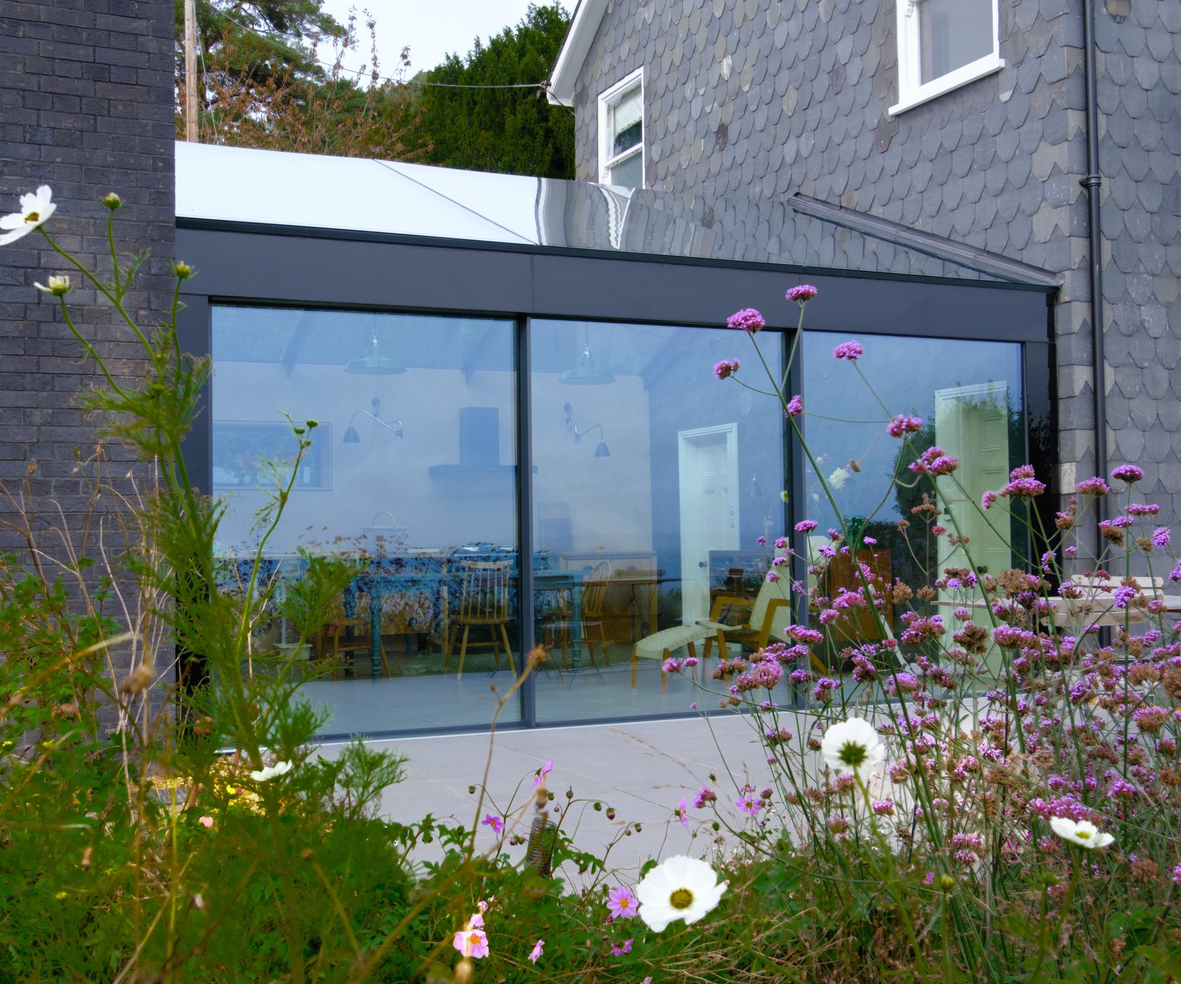 glass link extension between two buildings with slate tile finishes to external walls