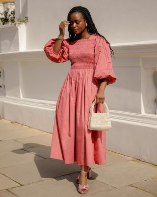 Woman wears a pink long sleeve smock dress with Loeffler Randall metallic heels.