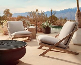 A pair of teak and rattan-effect lounge chairs on a sun terrace by a pool