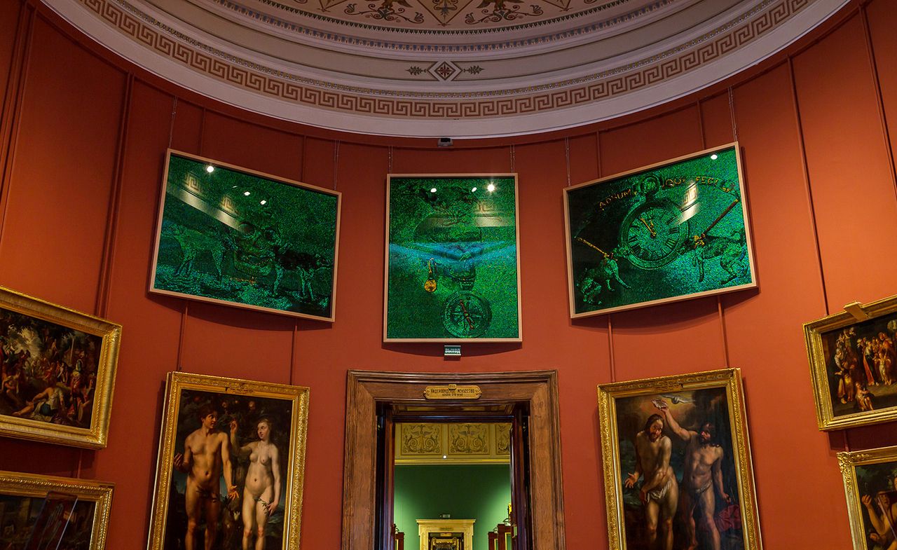 Jan Fabre&#039;s artwork is shown in the Old Masters in St Petersburg. His art is hung above classical art. Three paintings in all green with gold details, that look like they sparkle.